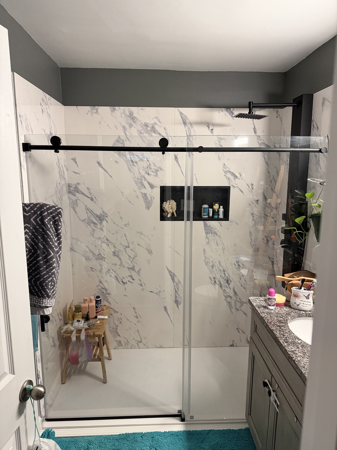 Bathroom with marble-look shower surround and glass shower door